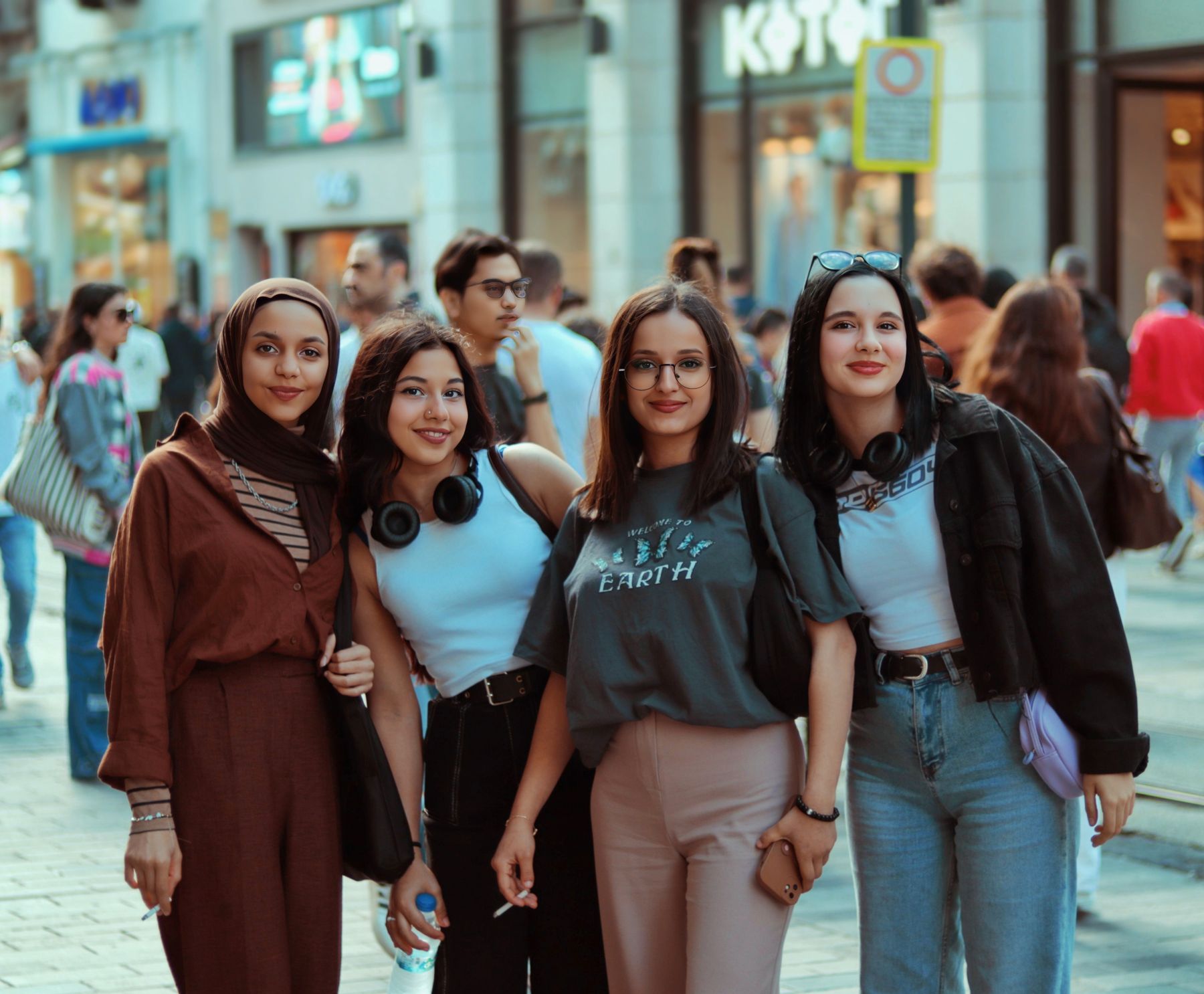 Four friends posing together on a busy street